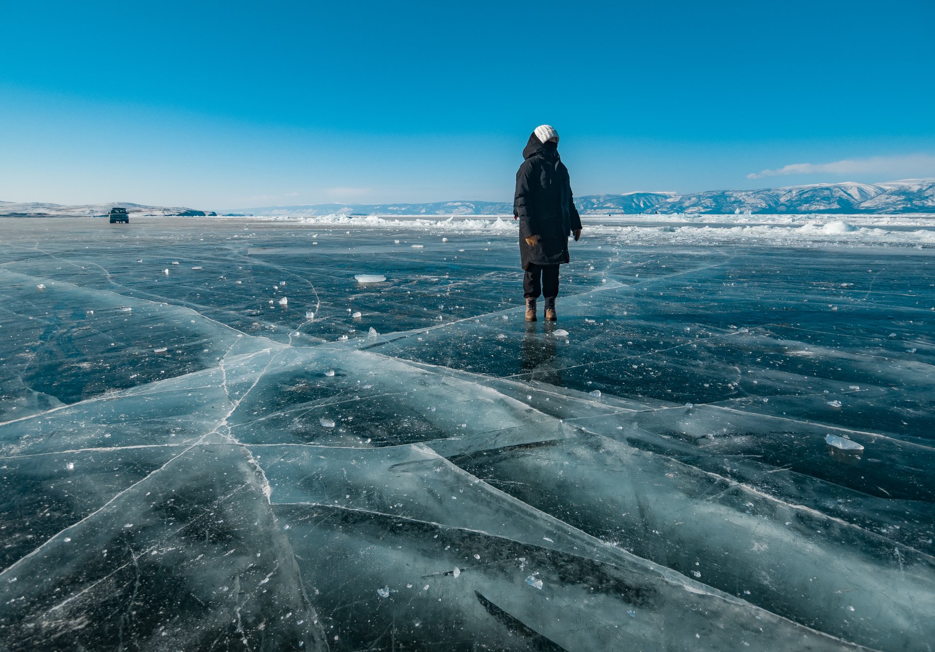 A tourist girl looks at the ice of Lake Baikal.
