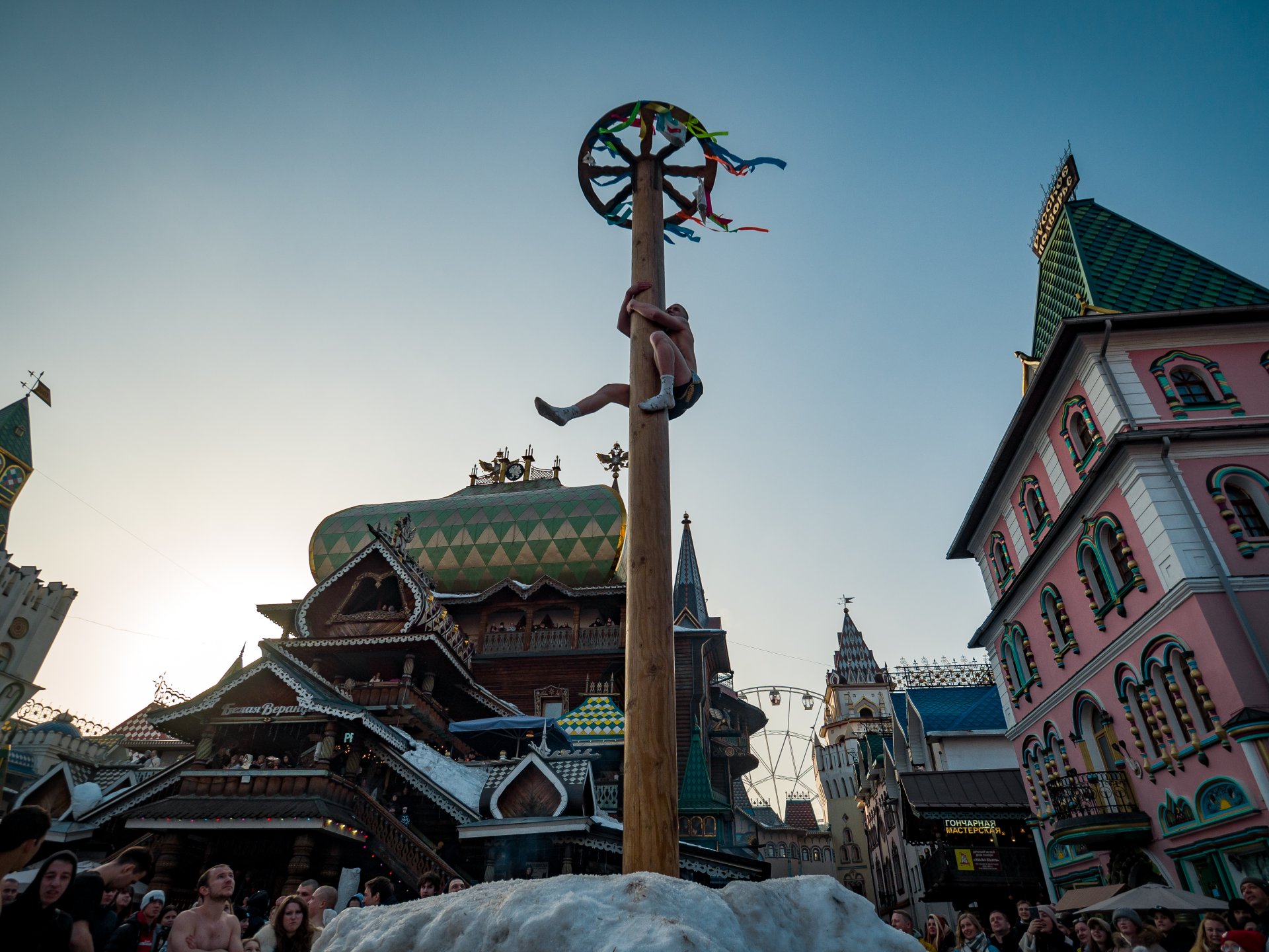 Young people try to pick up the gifts hung on top of the Maslenitsa pillar.