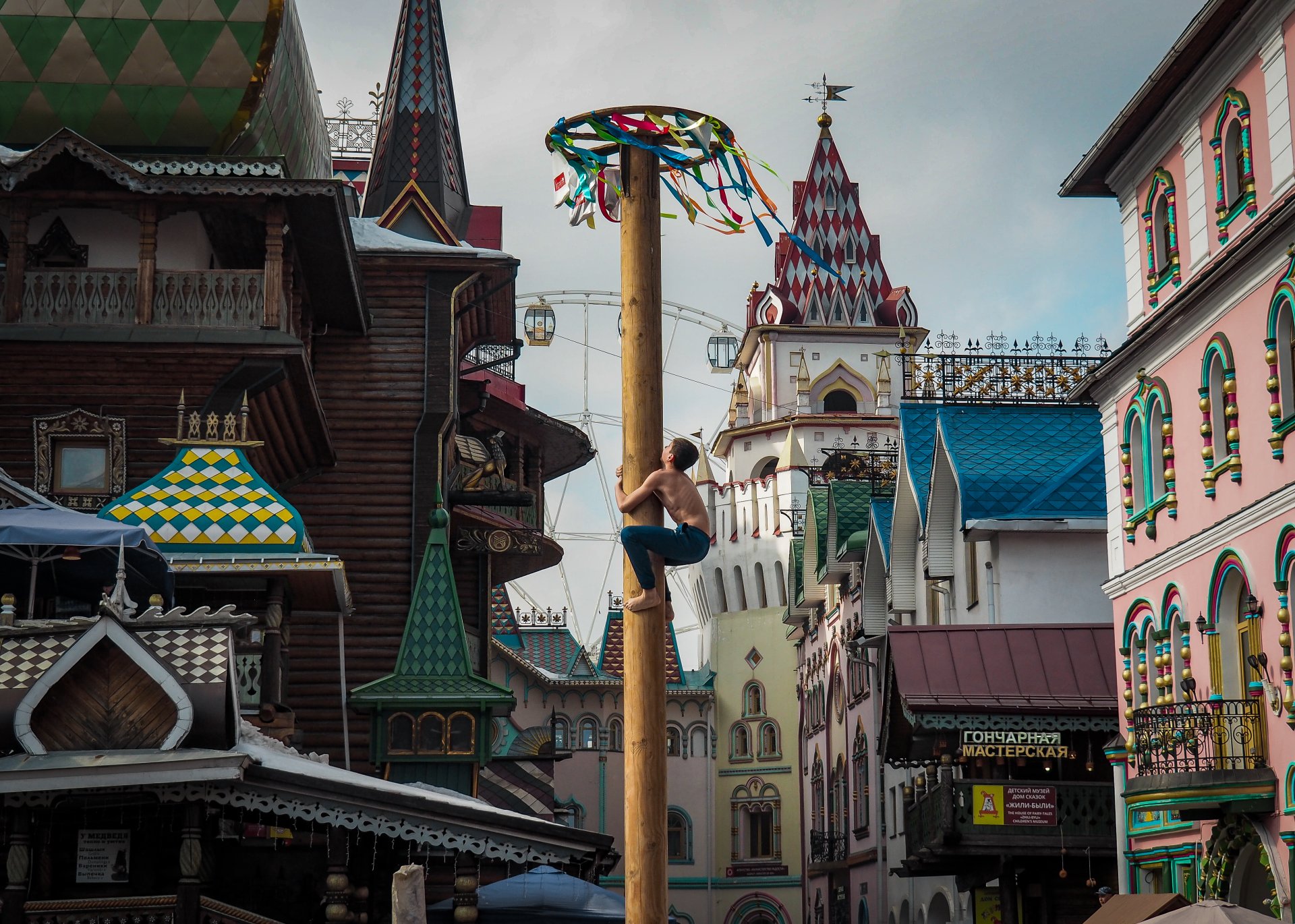 Young people try to pick up the gifts hung on top of the Maslenitsa pillar.